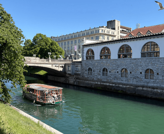 Boot fährt auf der Ljubljanica unter der Drachenbrücke durch