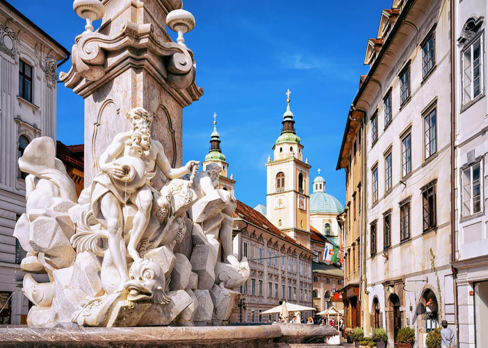 Brunnen auf dem Marktplatz von Ljubljana mit dem Dom als Sehenswürdigkeit im Hintergrund